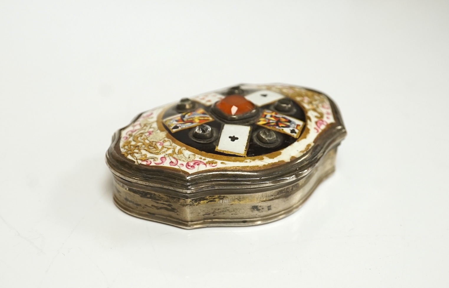 A continental white metal, enamel and two colour paste? set shaped oval snuff box, decorated with playing cards, unmarked, 67mm. Condition - poor